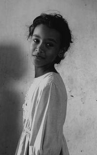 Portrait of smiling young woman standing against wall