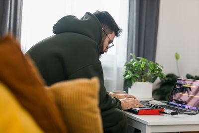 Side view of woman using digital tablet at home