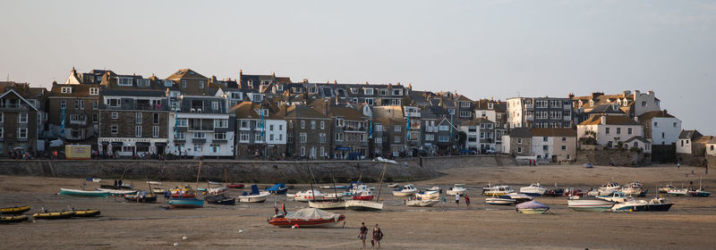 Boats in city by buildings against clear sky