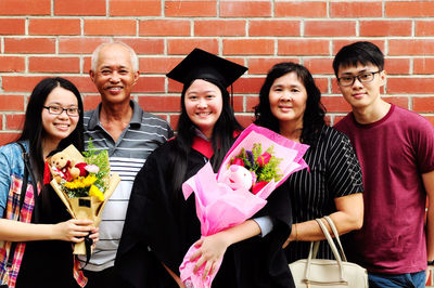 Portrait of family standing against brick wall during convocation