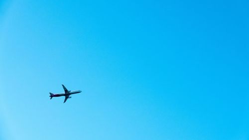 Low angle view of airplane against clear blue sky