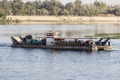 People on boat in river against trees