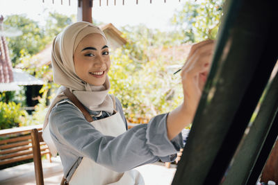 Portrait of smiling young woman standing in greenhouse