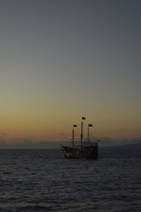 Sailboat sailing on sea against clear sky during sunset