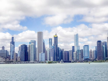 Sea by modern buildings against sky in city