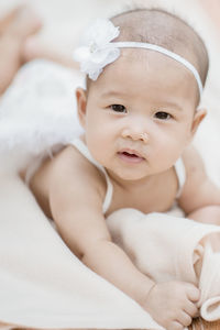 Portrait of cute baby girl wearing headband while lying on blanket