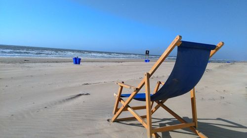 Lifeguard hut on beach against clear blue sky