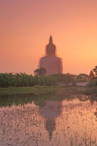 Scenic view of lake by building against orange sky