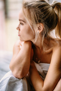 Close-up portrait of a beautiful young woman sitting on bed