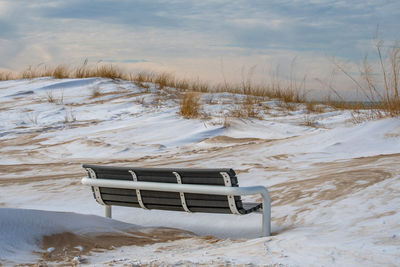 A frozen park bench sits on the beach, on the shores of lake michigan