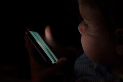 Close-up of baby girl holding mobile phone in darkroom