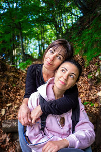 Cute lovely lovely mature lady mom woman hugging her brunette girl daughter in the woods.