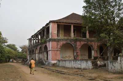 Man walking on old building against clear sky