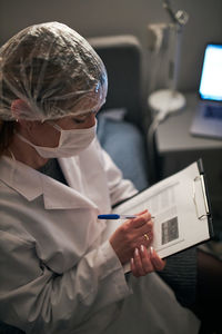 High angle view of doctor analyzing reports while sitting in hospital