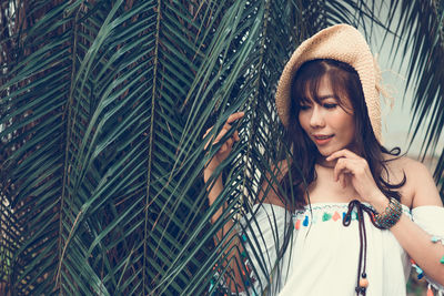 Woman standing by palm leaf