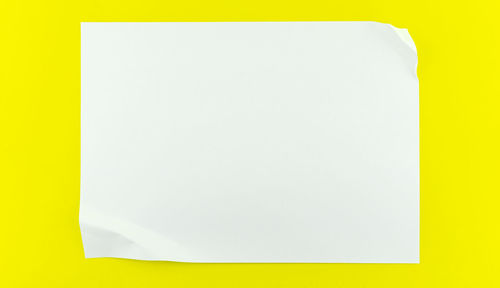 Directly above shot of white paper against yellow background