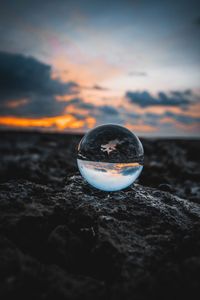 Water splashing on rocks by sea against sky during sunset