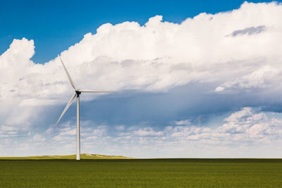 Wind turbines on field against sky