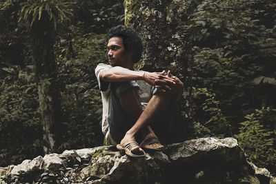 View of man sitting on rock in forest