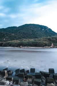 Scenic view of sea by mountains against sky