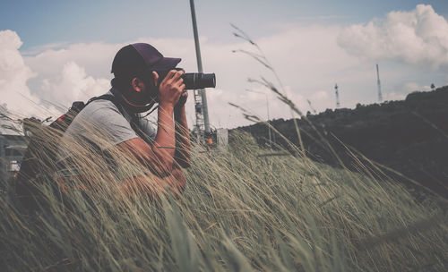 Man photographing on field against sky