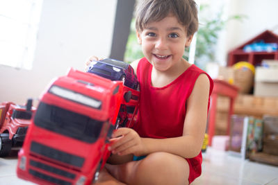 Portrait of boy playing with toy car while sitting on floor