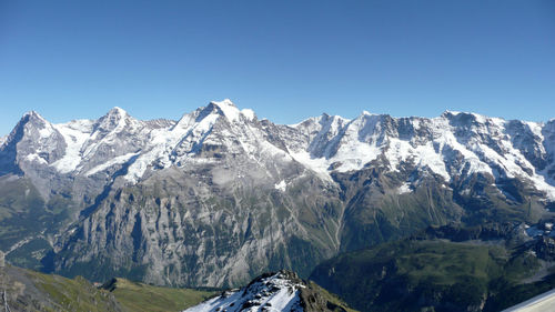 Scenic view of snowcapped mountains against clear blue sky