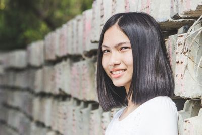 Portrait of attractive young smart woman smiling and standing in front of pillars.