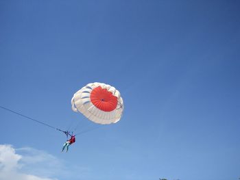 Low angle view of person parasailing against blue sky