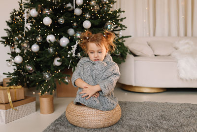 Portrait of cute girl playing with christmas tree at home