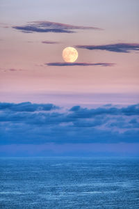 Full moon illuminated by the sunset light. taken over gyeongpo beach in gangneung, south korea