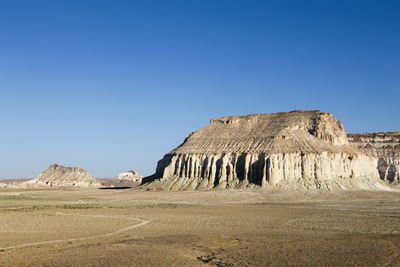 Low angle view of rock formations in desert against clear blue sky