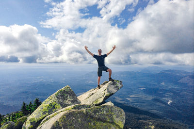 Full length of man jumping on cliff against sky