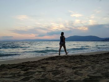 Man standing on beach against sky during sunset