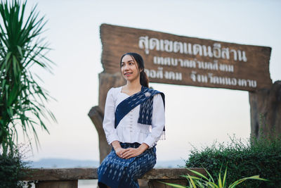 Portrait of young woman standing against text