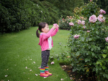 Full length of girl holding camera standing at park