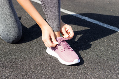 Low section of woman tying shoelace on road