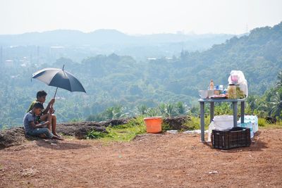 People sitting on mountain road against sky