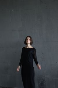 Young woman standing against wall