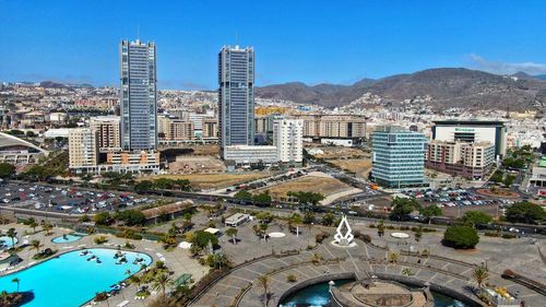 High angle view of city buildings against blue sky