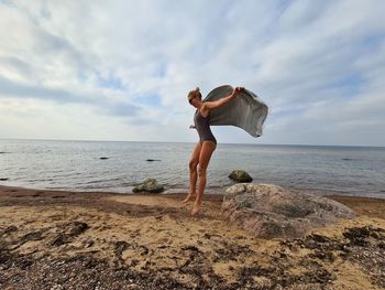 Jumping woman  on beach against sky