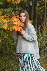 Young woman standing against plants