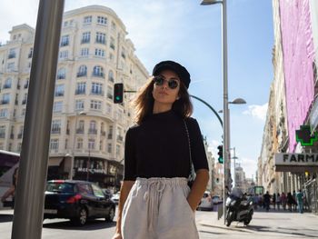 Young woman standing against buildings in city