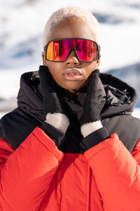 A african american woman wearing goggles standing in snowy mountain during winter	