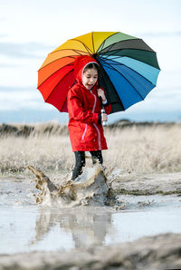 Woman with umbrella standing in water during rainy season