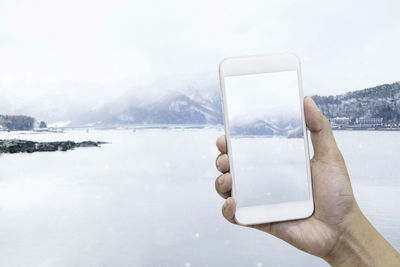 Hand holding smart phone in snow