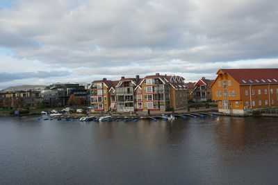 Buildings by river against sky in town