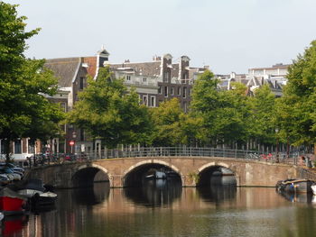 Bridge over river in city against clear sky