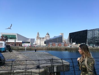 Woman in city against clear blue sky