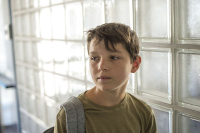 Cute boy looking away while standing by wall